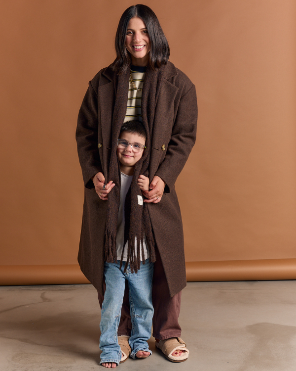 Woman and child wearing matching brown coats against a brown background